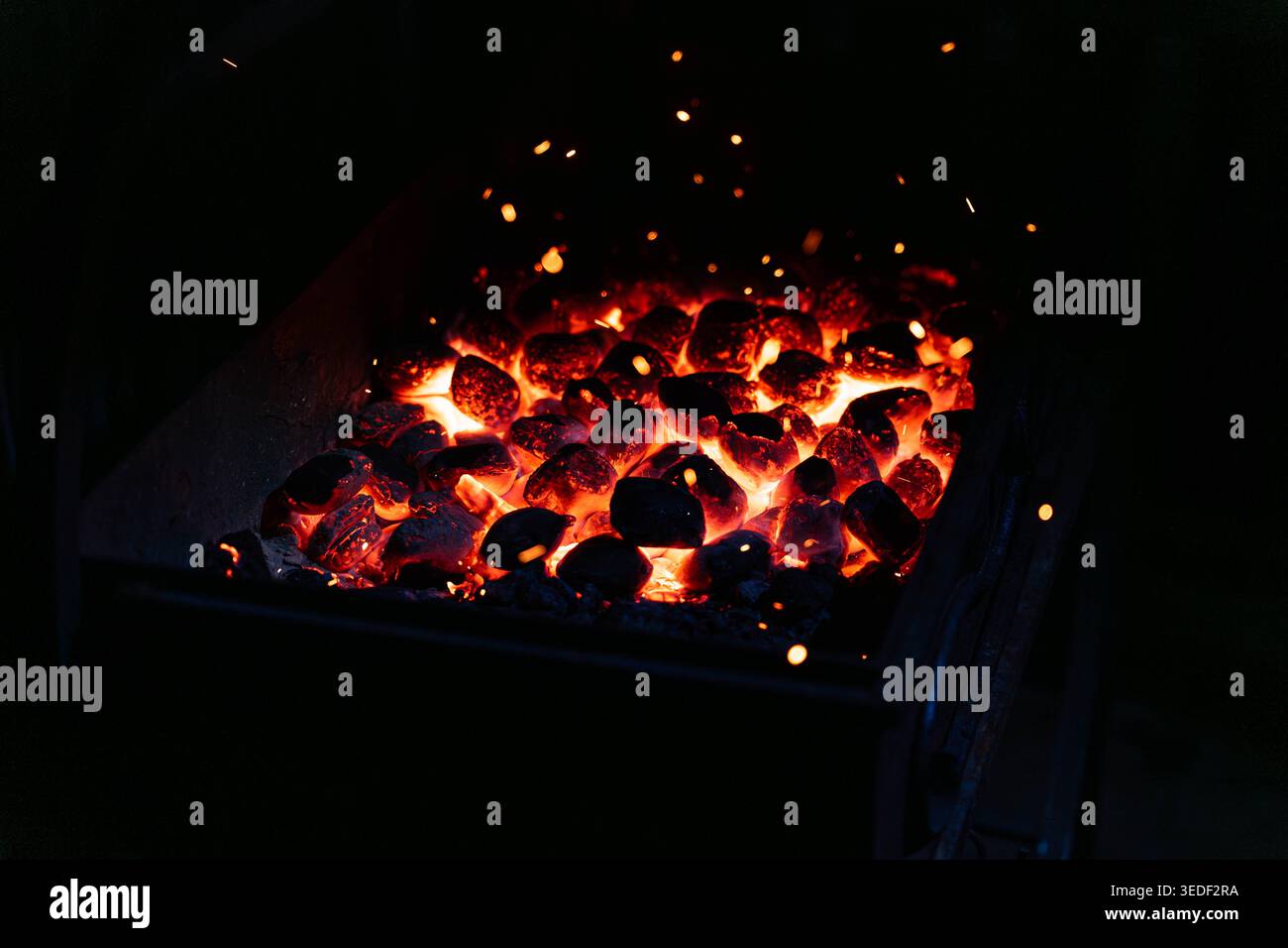Glowing Charcoal Embers In Grill Heat And Sparks, Closeup Of Redhot Coal Bed Inside Metal Grill, Streulicht Sparks Rising, Smoky Aroma, Vorwärmung Stockfoto
