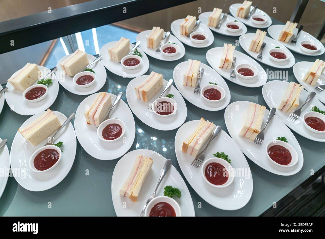 Eine lebhafte Auswahl an gut arrangierten Sandwiches mit Ketchup, perfekt für Veranstaltungen. Die elegante Präsentation verleiht jedem Treffen einen Hauch von Klasse Stockfoto