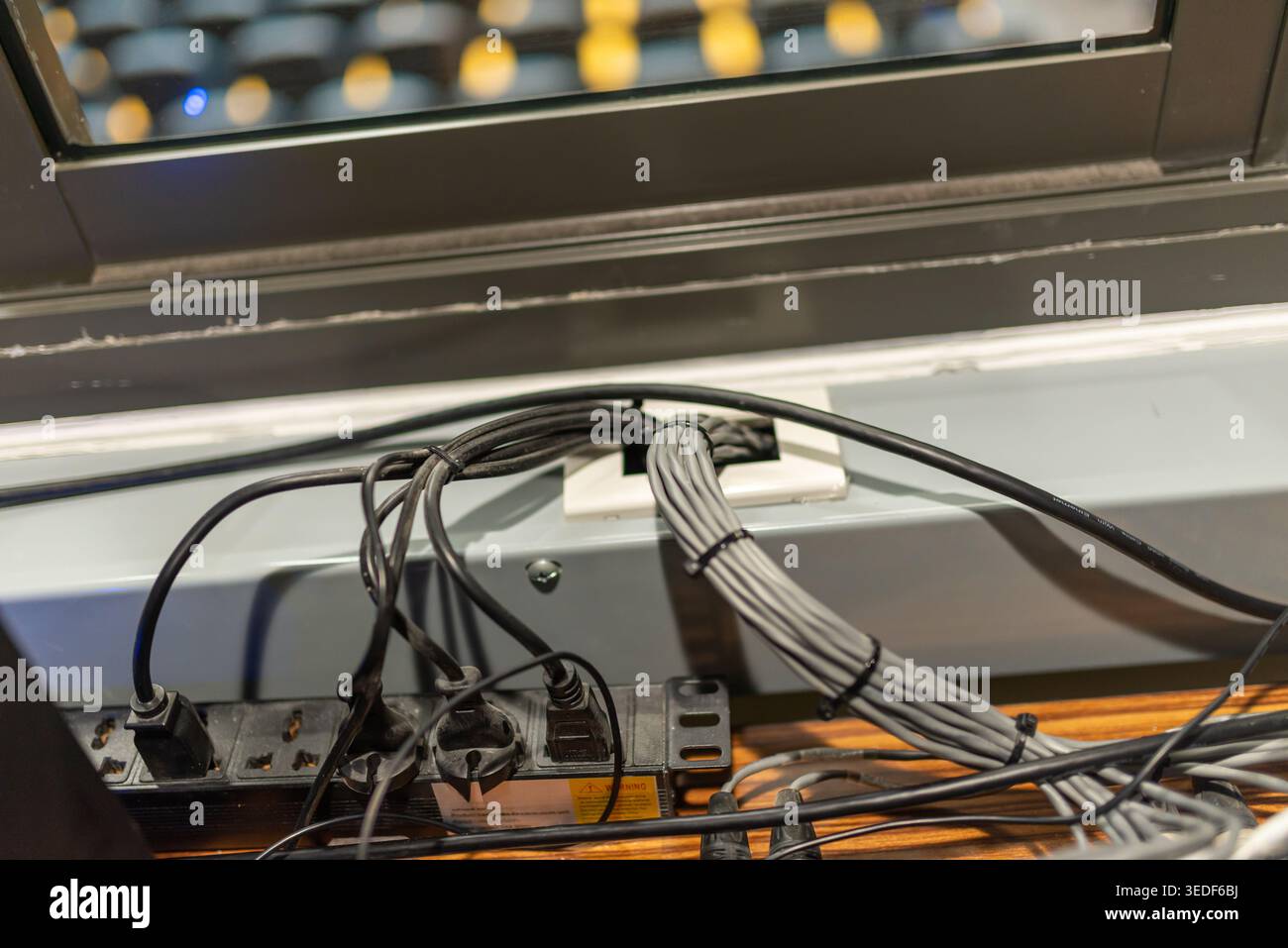 Dieses Bild zeigt organisierte Kabel in der Nähe eines Fensters in einer Büroumgebung. Es unterstreicht die Bedeutung des Kabelmanagements für einen aufgeräumten Arbeitsplatz. Stockfoto
