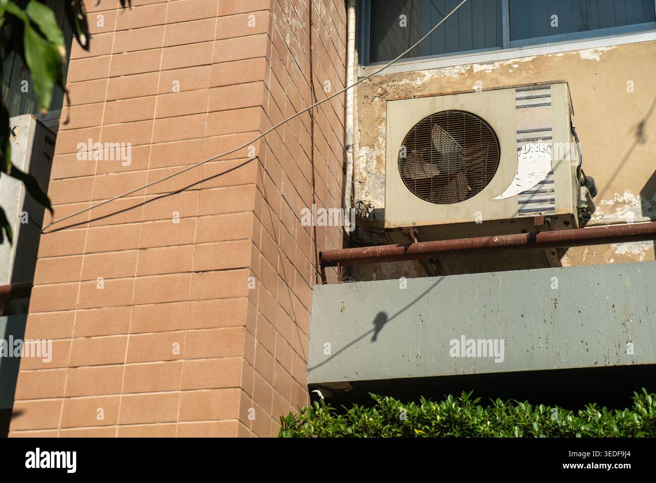 Eine Klimaanlage, die an der Außenfassade des Gebäudes montiert ist, zeigt städtische Architektur. Dieses Bild hebt die Kühltechnologie hervor, die für Komfort i unerlässlich ist Stockfoto