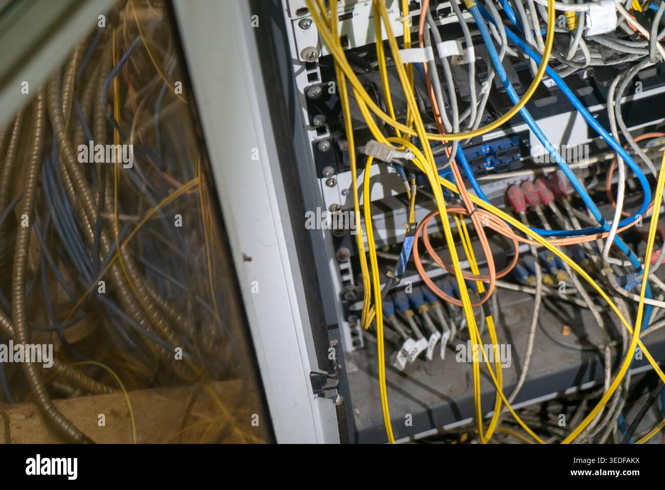 Eine Nahaufnahme eines Server-Racks mit unordentlichen Kabeln und Drähten. Die chaotische Anordnung unterstreicht die Komplexität moderner Netzwerkgeräte. Stockfoto