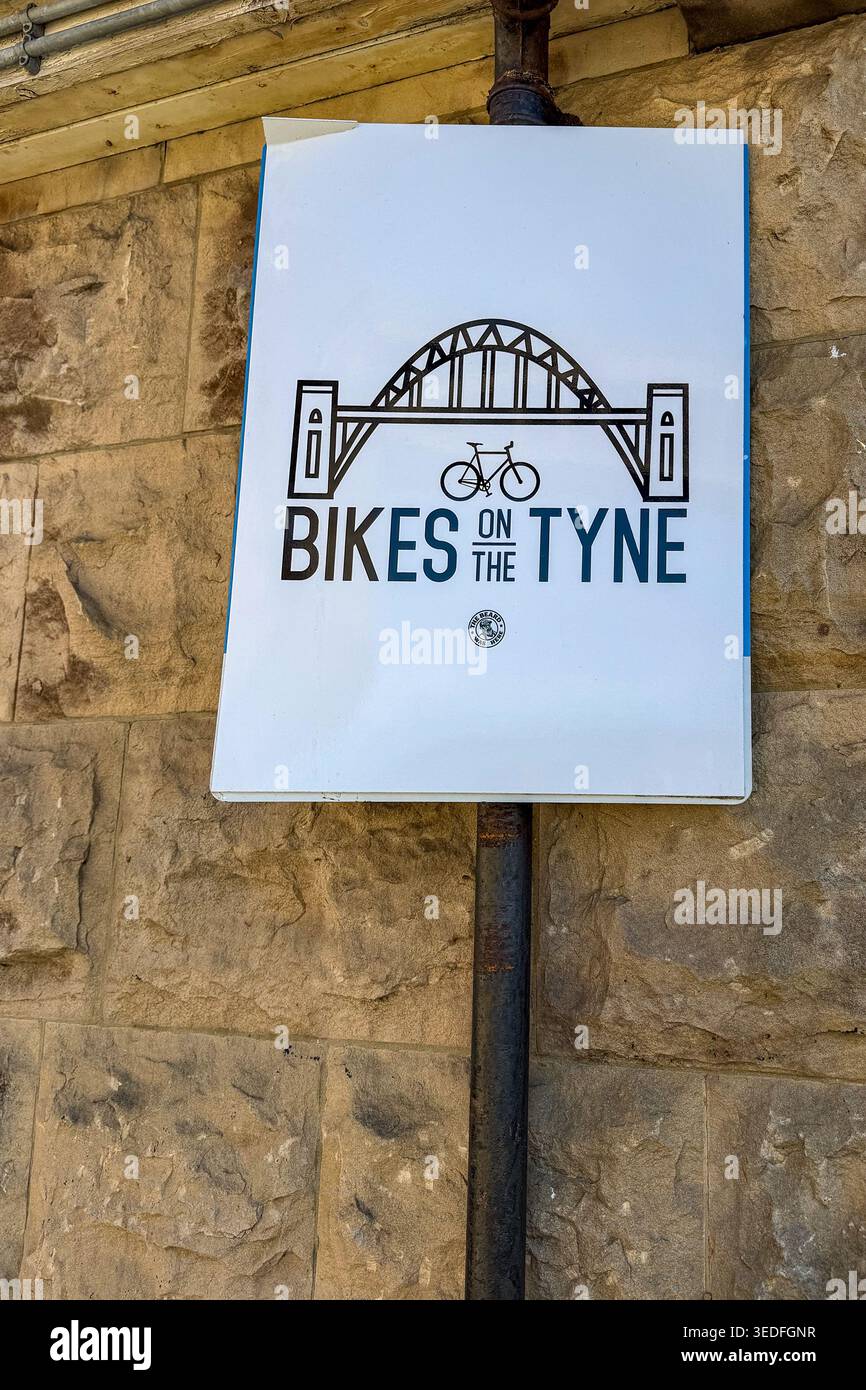 Ein Schild mit dem Titel Bikes on the Tyne mit einer Illustration der Tyne Bridge, die an einer Steinmauer in Newcastle befestigt ist Stockfoto