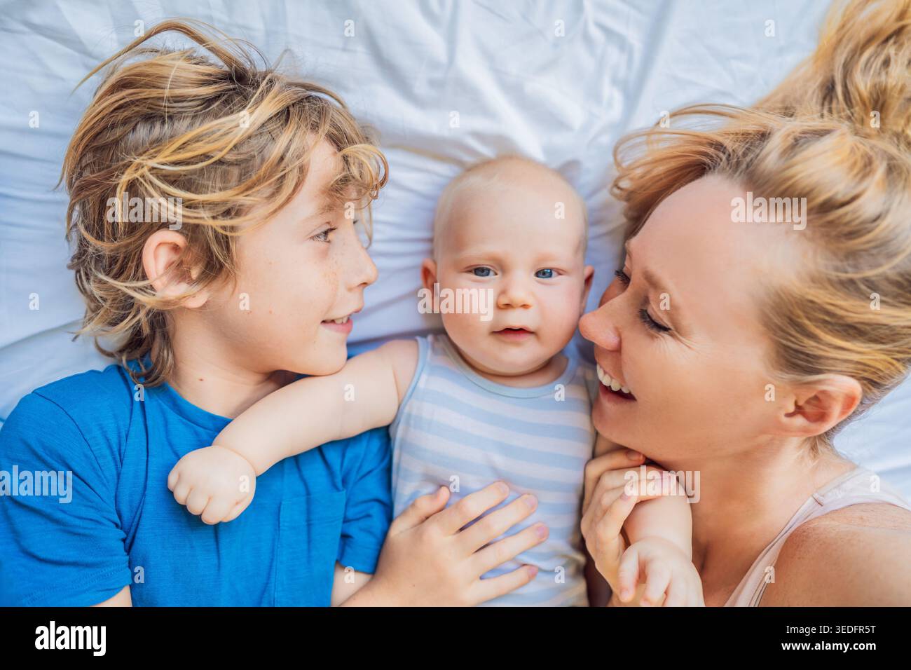Mutter liegend mit zwei Söhnen, neugeborenem Baby und älterem Kind zu Hause. Liebevolle Familie, die Zeit miteinander verbringt, sich verbindet und entspannt. Mutterschaft Stockfoto