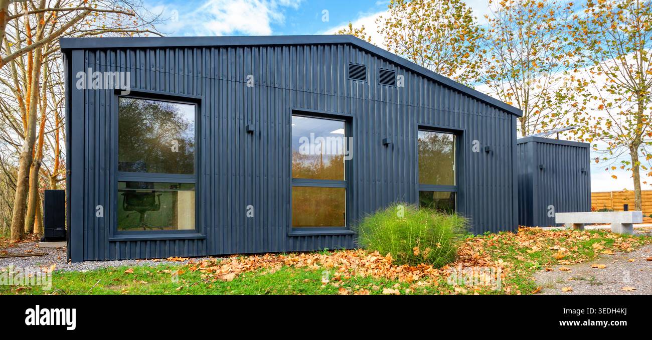 Nachhaltiger Versandcontainer modernes Haus mit Wellblechverkleidung im Herbst Stockfoto