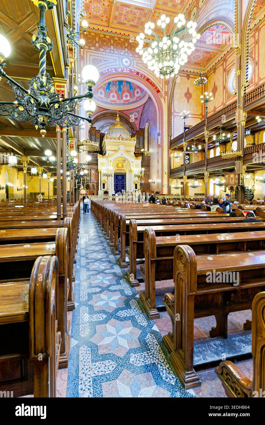 Die Leute laufen in die Dohany Street Synagoge. Die Holzbänke und die großen Kronleuchter erfüllen den Raum mit Licht. Stockfoto