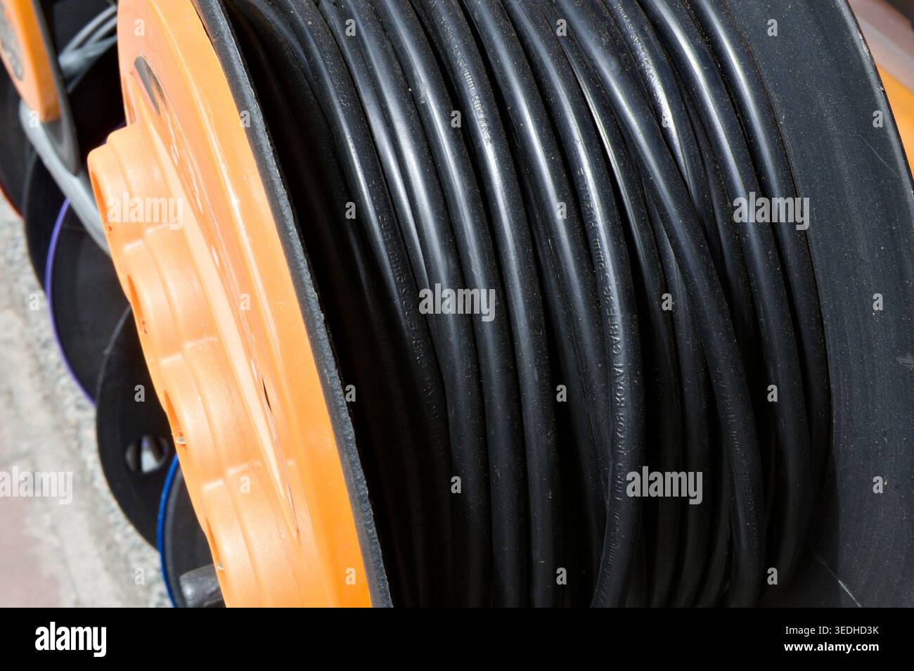 Nahaufnahme von schwarzen Kabeln, die auf einer orangefarbenen Rolle gewickelt sind Stockfoto