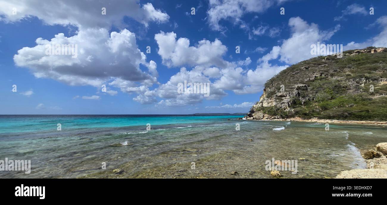 Tropische Bucht mit türkisfarbenem karibischem Wasser und felsiger Küste unter blauem Himmel - Smartphone-aufgenommenes Stockfoto