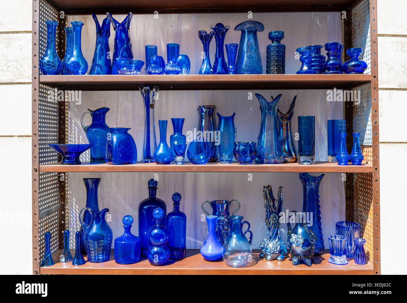 Auswahl an dekorativen blauen Glasvasen, Flaschen und Schüsseln auf Holzregalen Stockfoto