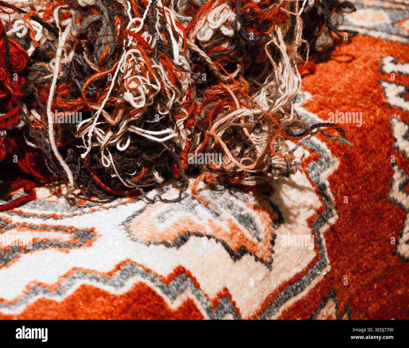 Orientalische Teppiche und Wollfäden auf dem Markt. Konzept „vom Material zum Produkt“. Selektiver Fokus auf die Gewinde. Veraltetes Foto. Stockfoto