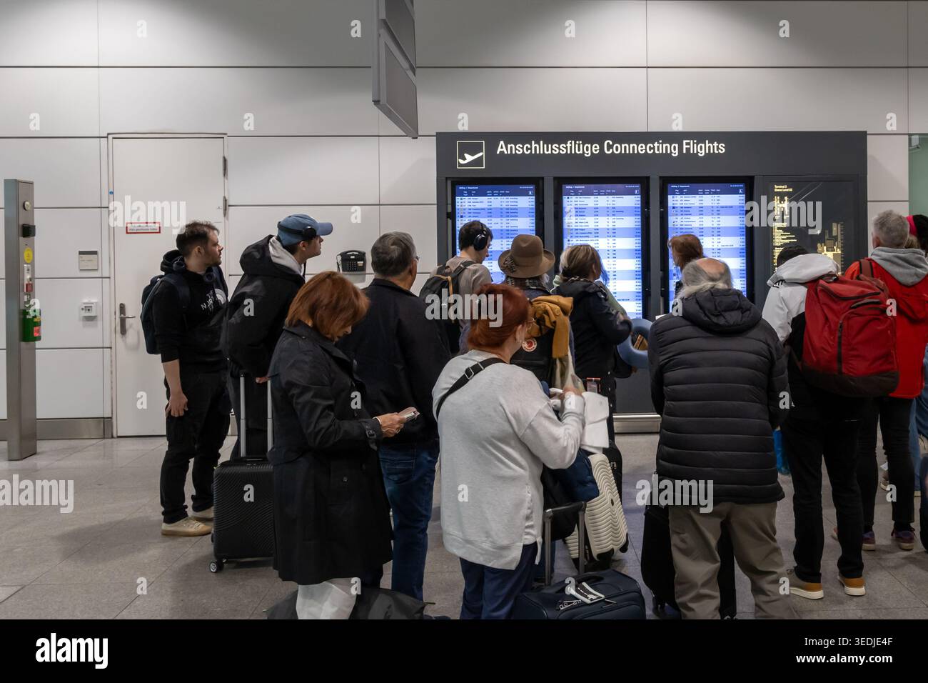 Passagiere, die Informationen zu Anschlussflügen am Flughafen abrufen Stockfoto