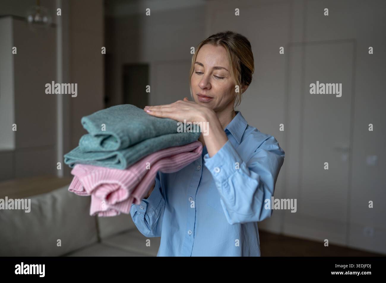 Zufriedene Frau fühlt sich weich frisch gewaschene Pullover in den Händen und genießt ein angenehmes, weiches Material Stockfoto