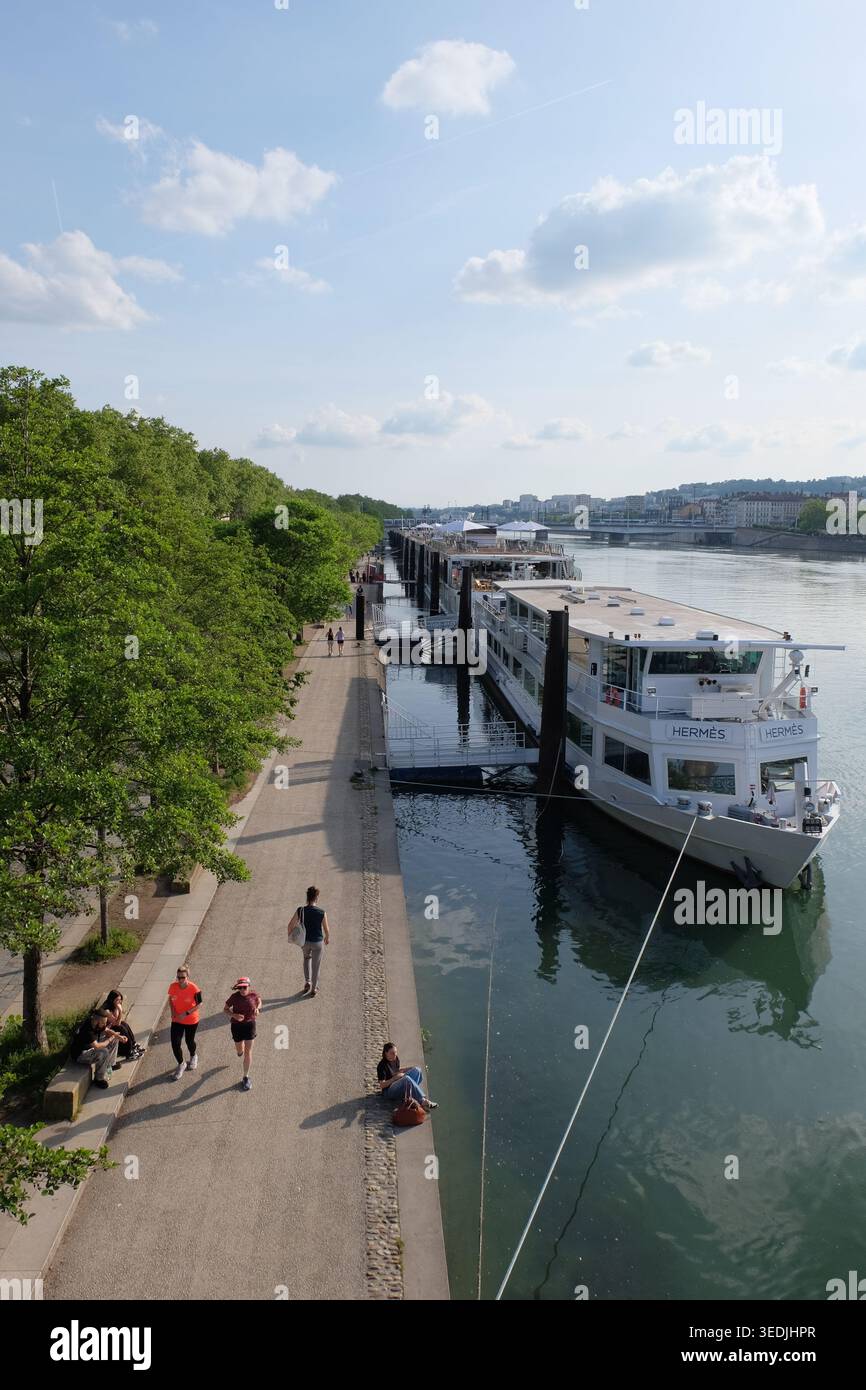 In Lyon, Frankreich, joggen und spazieren gehen Sie auf den Rhonekaien neben angedockten Flussbooten. Stockfoto