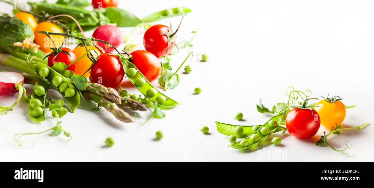 Frische grüne Erbsenschoten mit Sprossen, Rettich, Tomaten und grünem Spargel auf weißem hölzernem Hintergrund. Konzept der gesunden Ernährung, frisches Gemüse. Stockfoto