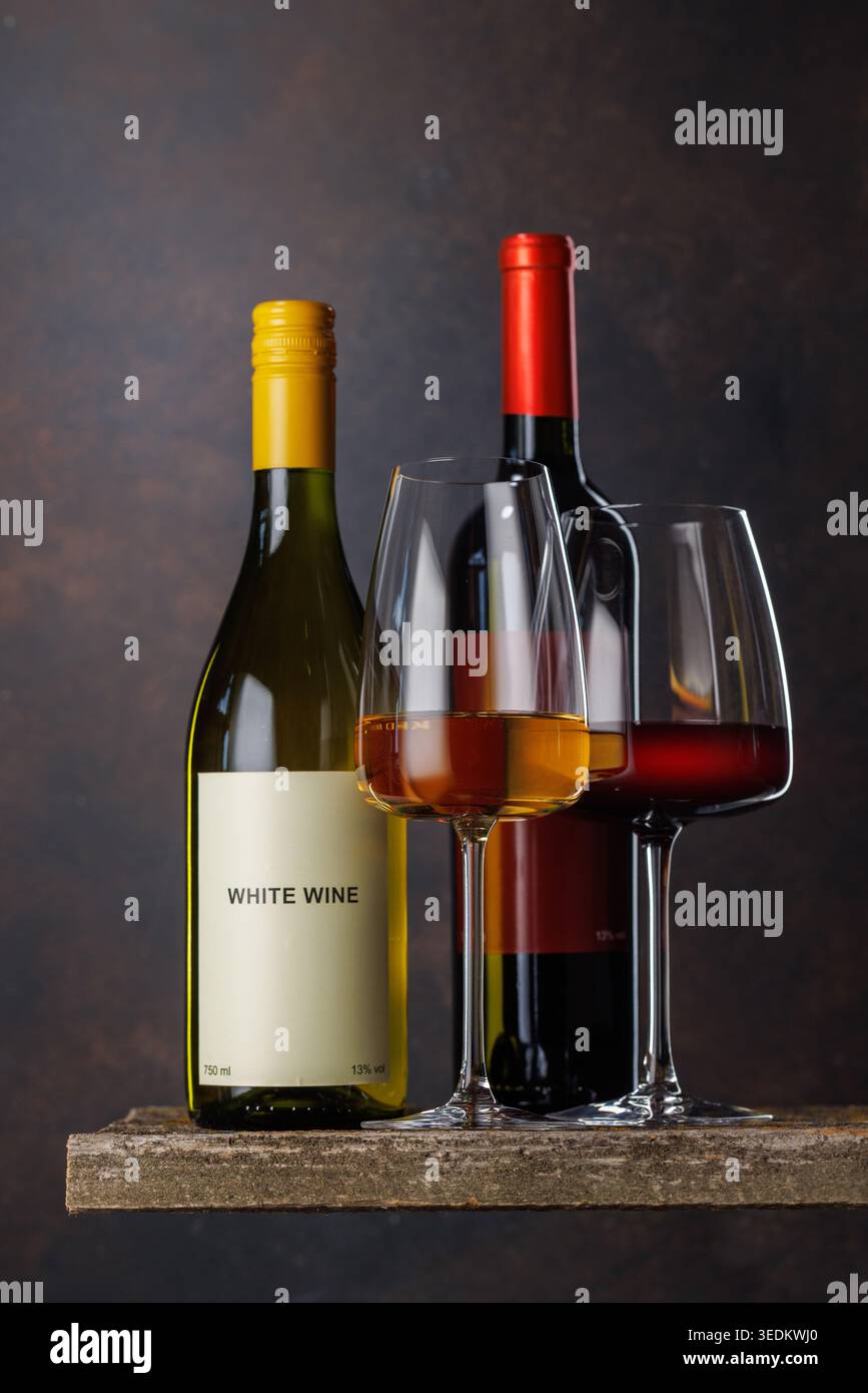 Gläser Rot- und Weißwein mit Flaschen auf dunklem Hintergrund Stockfoto