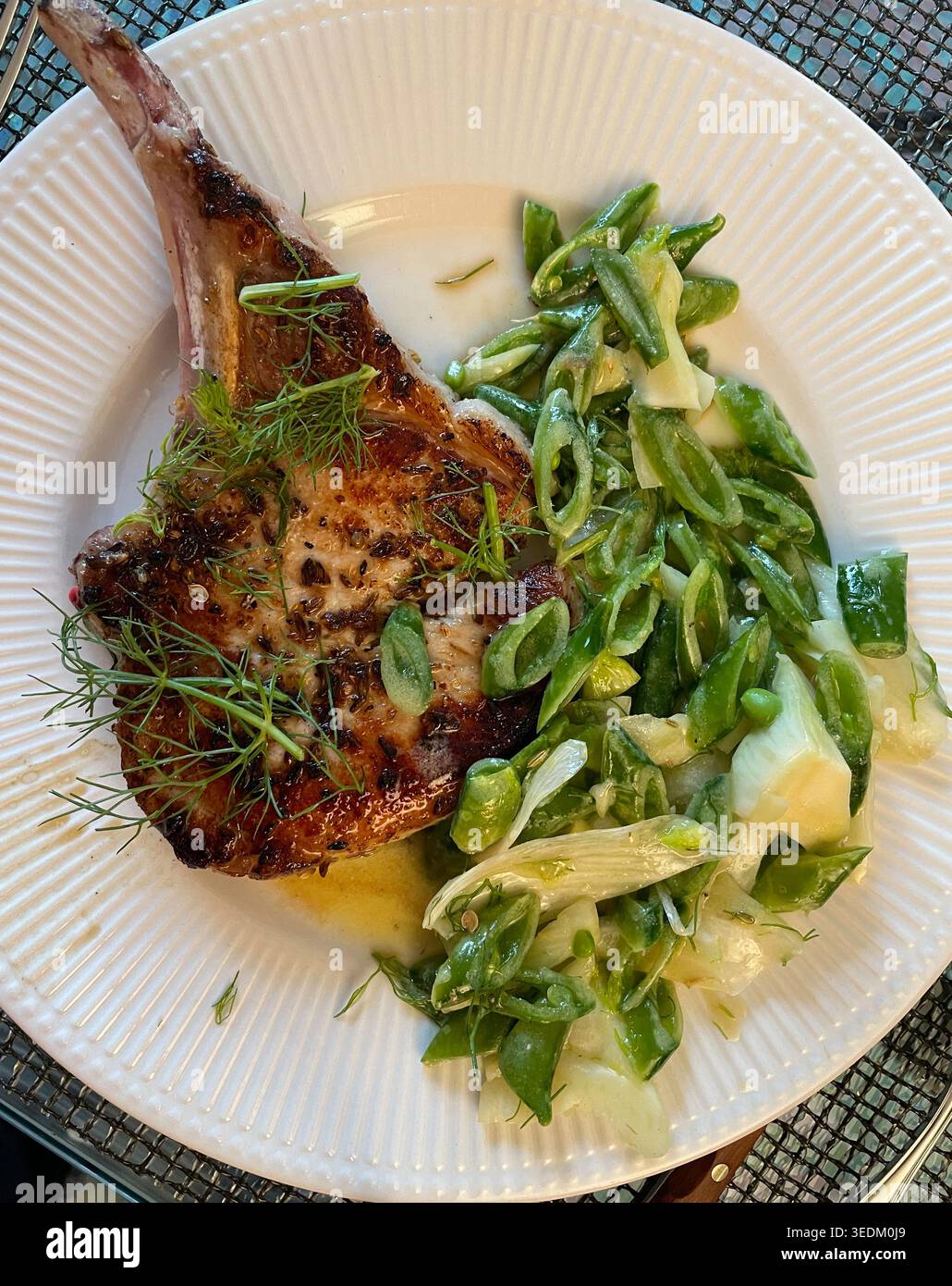 Gourmet-Vorspeise aus gewürztem Schweinekotelett mit Knabbererbsen-Slaw auf einem weißen porzellanteller, 2026, USA Stockfoto