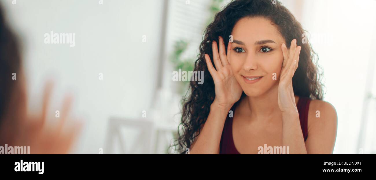 Die Frau schaut sich ihr Spiegelbild im Spiegel an und übt zu Hause Gesichtsausdrücke aus Stockfoto