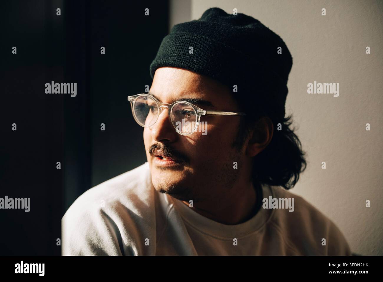 Junger Geschäftsmann mit Brille und schwarzer Mütze im Büro Stockfoto