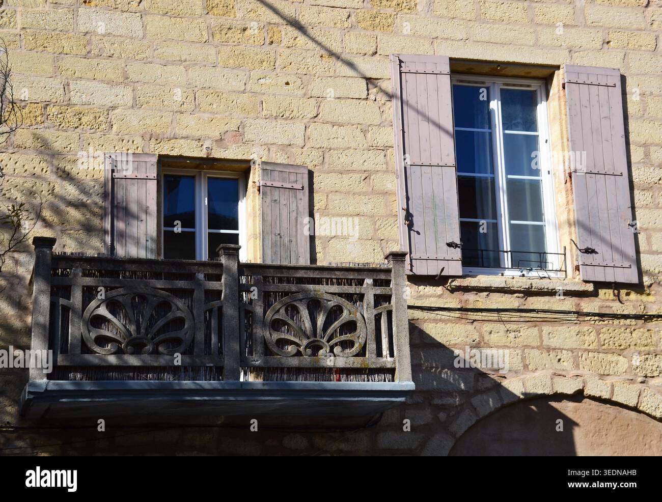 Traditionelle Steinfassade mit Holzläden und einem dekorativen geschnitzten Balkon im historischen Dorf Sommieres, Frankreich. Stockfoto