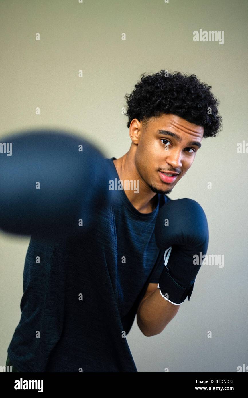 Porträt eines jungen Mannes, der Boxen vor farbigem Hintergrund übt Stockfoto