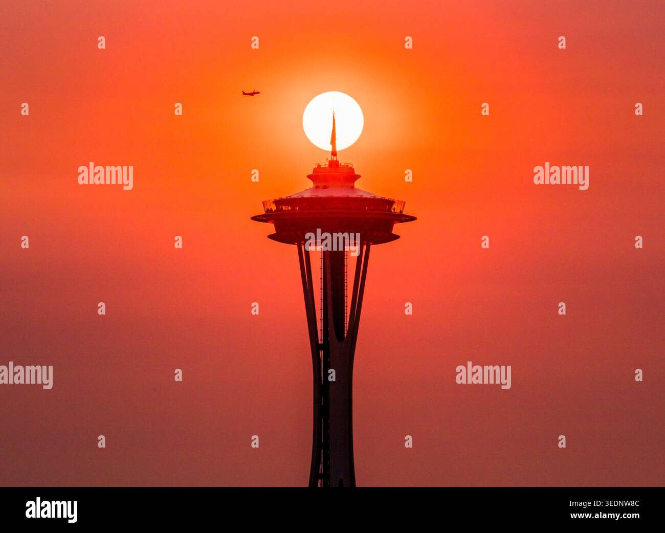 Die ikonische Space Needle und das Flugzeug im Flug, die sich gegen die späte Sonne am Nachmittag abschirmen. Seattle, Washington, USA Stockfoto