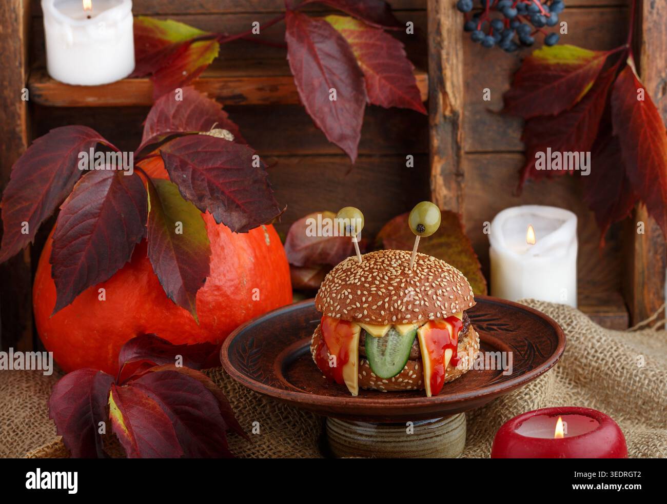 Halloween. Monster Burger mit Sesambrötchen, Rindfleisch mit Cheddar-Käse, Gurke, Ketchup und Oliven. Das Konzept des Urlaubs. Ein Kindersandw Stockfoto