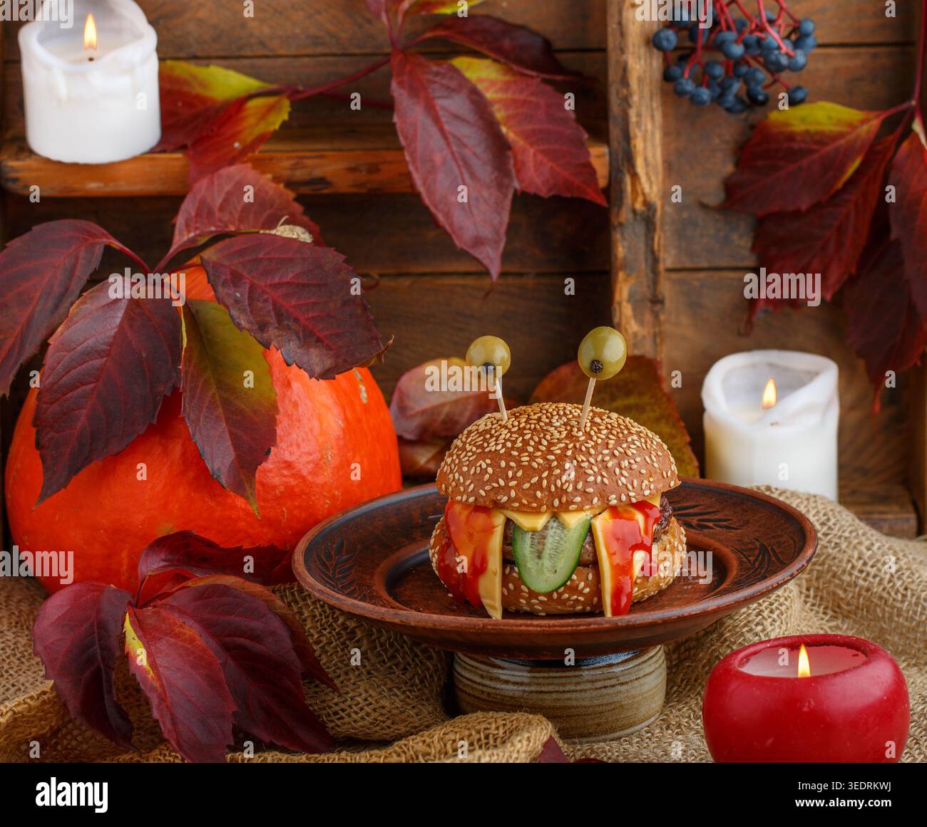 Halloween. Monster Burger mit Sesambrötchen, Rindfleisch mit Cheddar-Käse, Gurke, Ketchup und Oliven. Das Konzept des Urlaubs. Ein Kindersandw Stockfoto