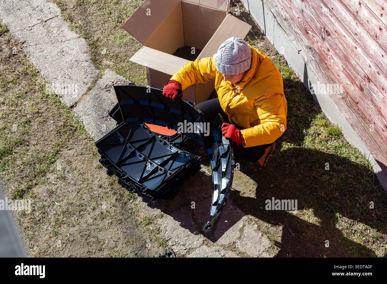 Modulares Kompostsystem mit stapelbaren Kunststoffteilen, die von Landbewohnern in der Nähe des Landes ausgepackt werden. Stockfoto