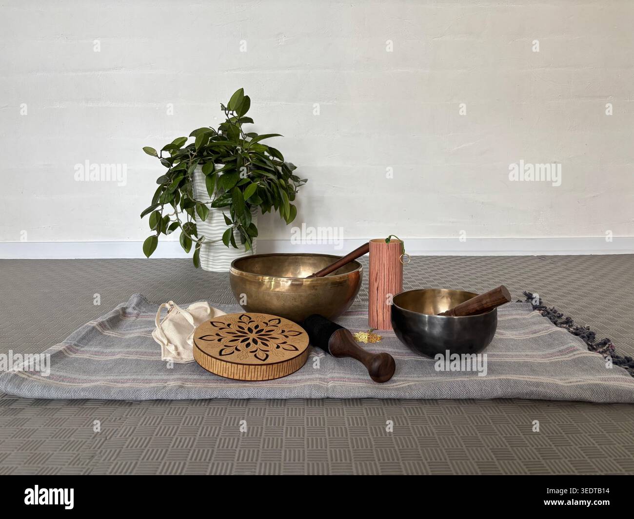 Klangheilungs- und Yoga-Meditationseinrichtung mit Klangschalen, Holzinstrumenten und natürlichem Dekor auf Textilmatte. Konzept der Entspannungsachtsamkeit und Wellness-Praxis Stockfoto