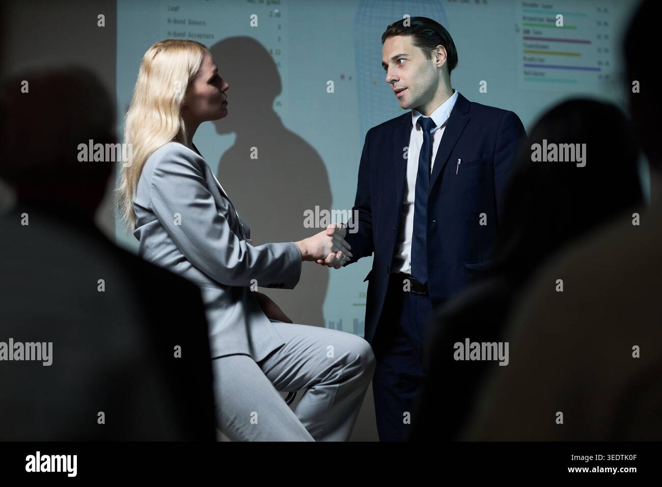 Geschäftsmann und Geschäftsfrau schütteln während der Präsentation die Hand Stockfoto