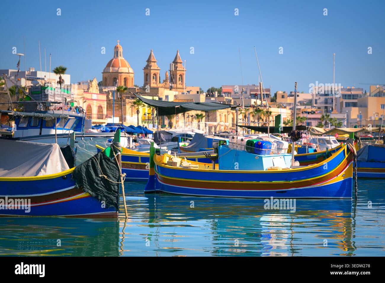 Blaue Luzzu-Boote im Hafen des mediterranen Fischerdorfes an einem Sommermorgen, Marsaxlokk, Malta. Stockfoto