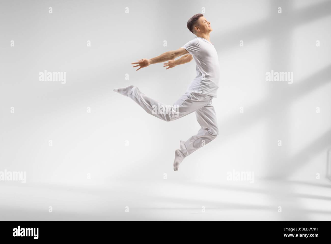 Der Typ in weißen Kleidern tanzt modernes Ballett in einem Studio Stockfoto