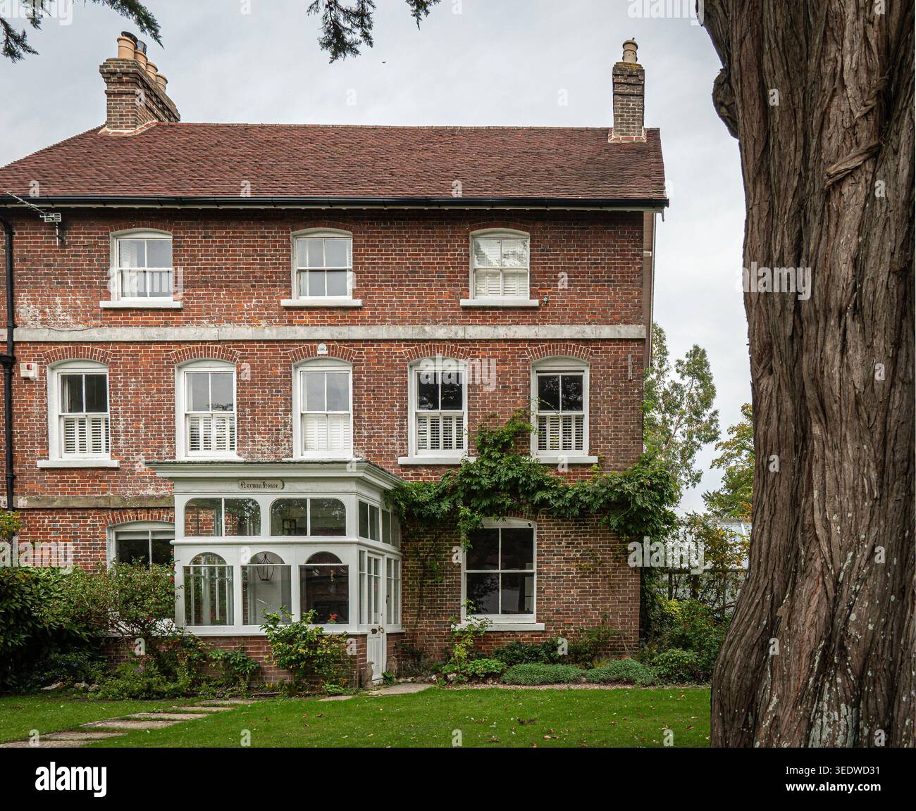Norman House in Westbourne, West Sussex. Dieses attraktive Haus hat eine weiße Veranda und Schiebefenster, in einem Dorf gelegen. Stockfoto