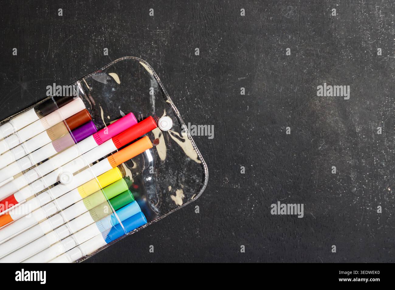 Farbenfrohe Marker in einem durchsichtigen Etui auf einer Tafel. Kunst- und Bildungsbedarf. Kreativitätskonzept. Bunte Stifte. Hochwertige Fotos Stockfoto