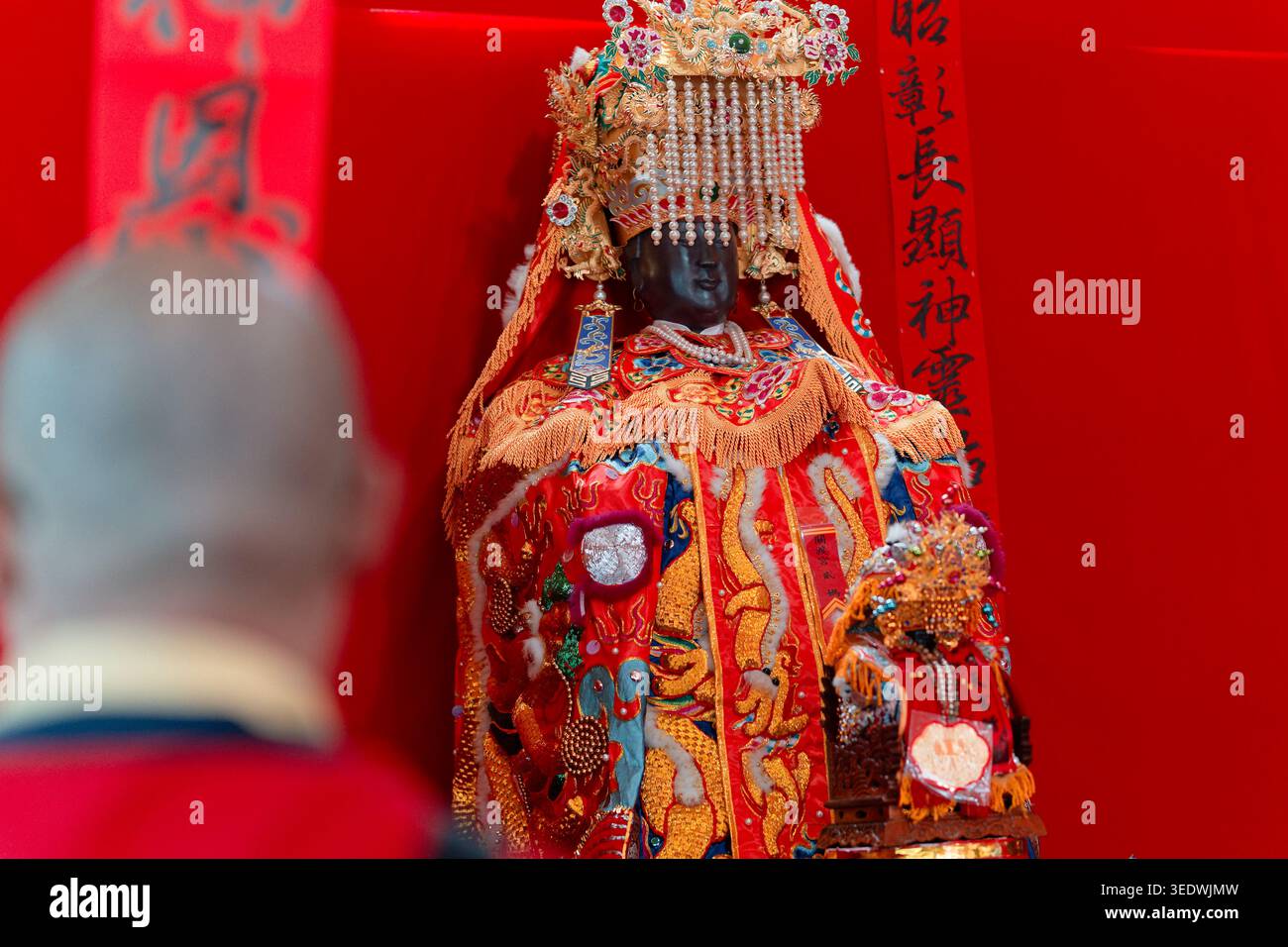 Taipeh, Taiwan - 29. März 2025: Ein Mann schaut feierlich auf die Guandu Mazu-Gottheit-Statue vor einem roten Schrein während der Wallfahrt in Neihu. Stockfoto