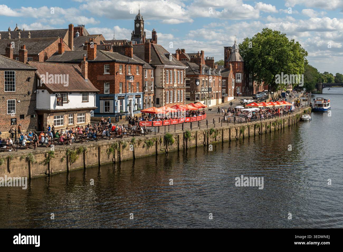 Menschen und Touristen, die im Sommer im Freien an der Uferpromenade des Flusses Ouse speisen, in York, England Stockfoto