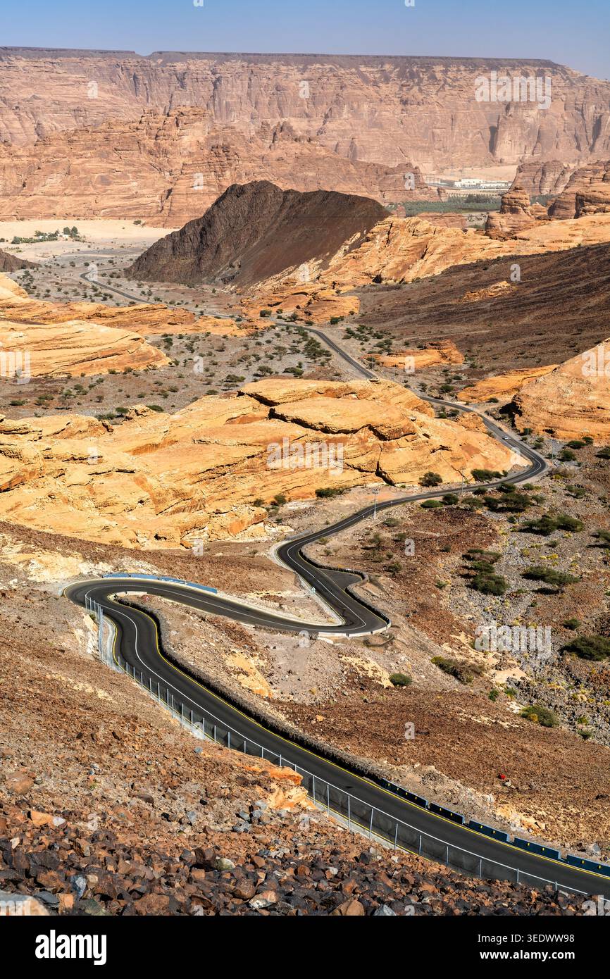 Eine gewundene Asphaltstraße schlängelt sich durch die dramatischen Sandsteinformationen und die Wüstenschlucht von Alula, Saudi-Arabien. Stockfoto