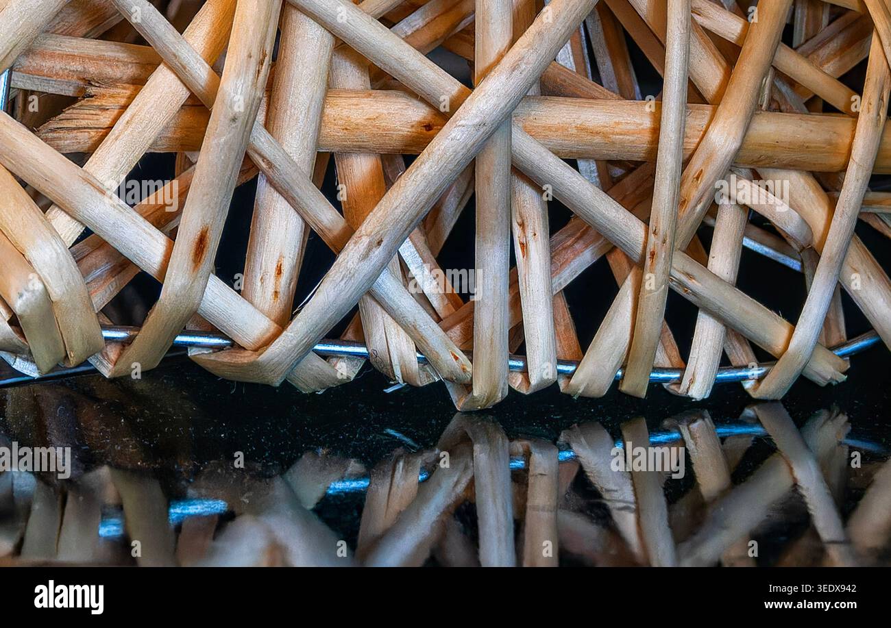 Ein abstraktes Mischmasch aus Holzstäben, das auf einer schwarzen Oberfläche reflektiert wird Stockfoto
