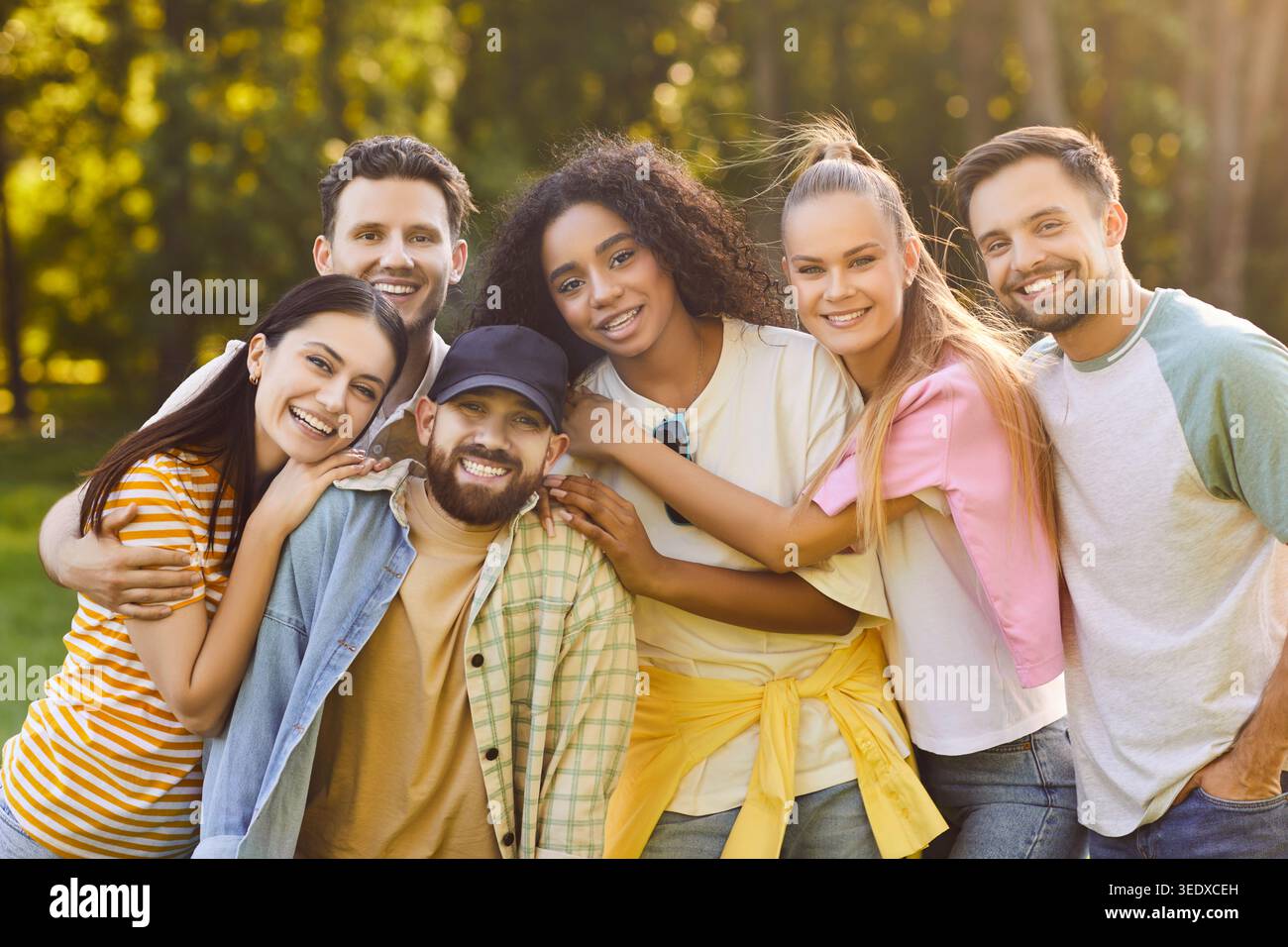 Freunde, die im Freien glücklich sind, eine Gruppe junger Erwachsener, die eng zusammenstehen und einander umarmen Stockfoto