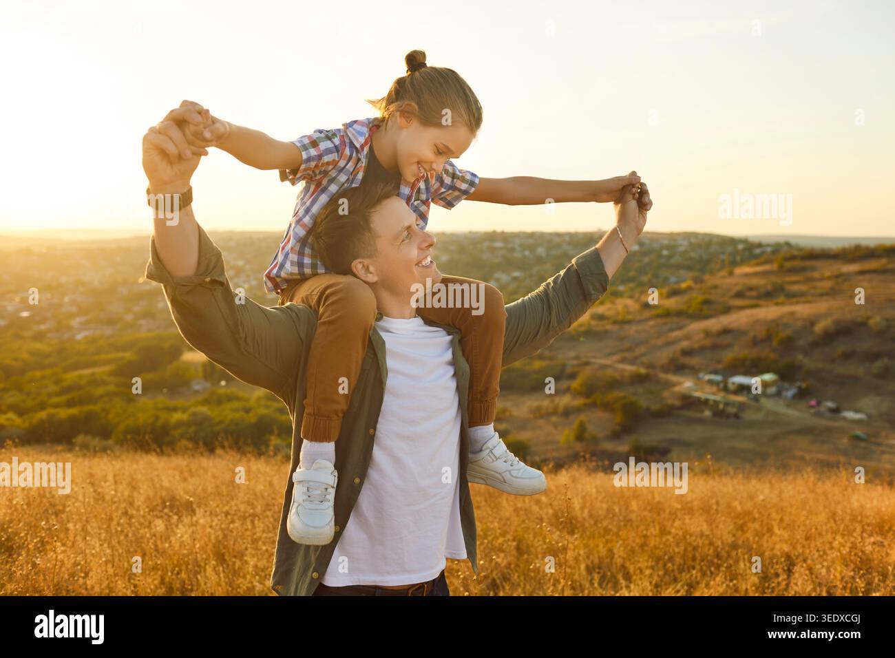 Glücklicher Vater und Sohn genießen die gemeinsame Zeit bei Sonnenuntergang, Kind reitet auf Schultern Stockfoto