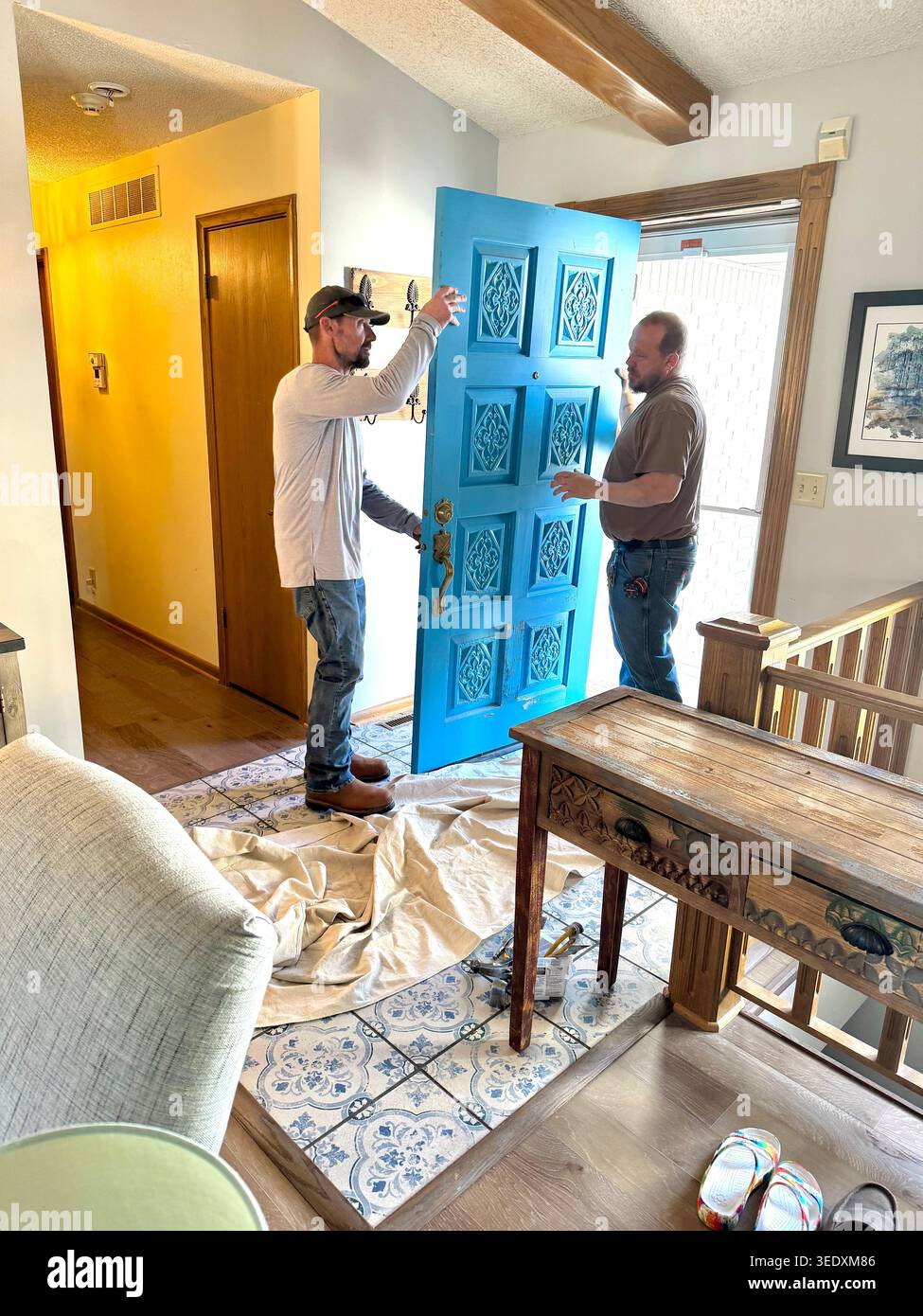 Zwei kaukasische Arbeiter entfernen in einem Wohnhaus in Wichita, Kansas, USA, eine von der Sonne beschädigte Haustür. Stockfoto