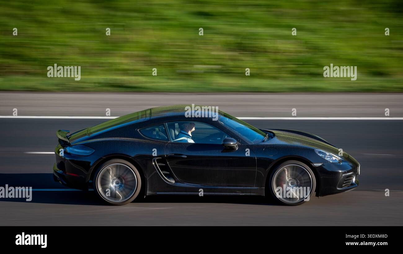 Schwarzer Porsche Cayman-Wagen, der in Richtung Morgenlicht fährt, M65 Altham, Lancashire, England Stockfoto