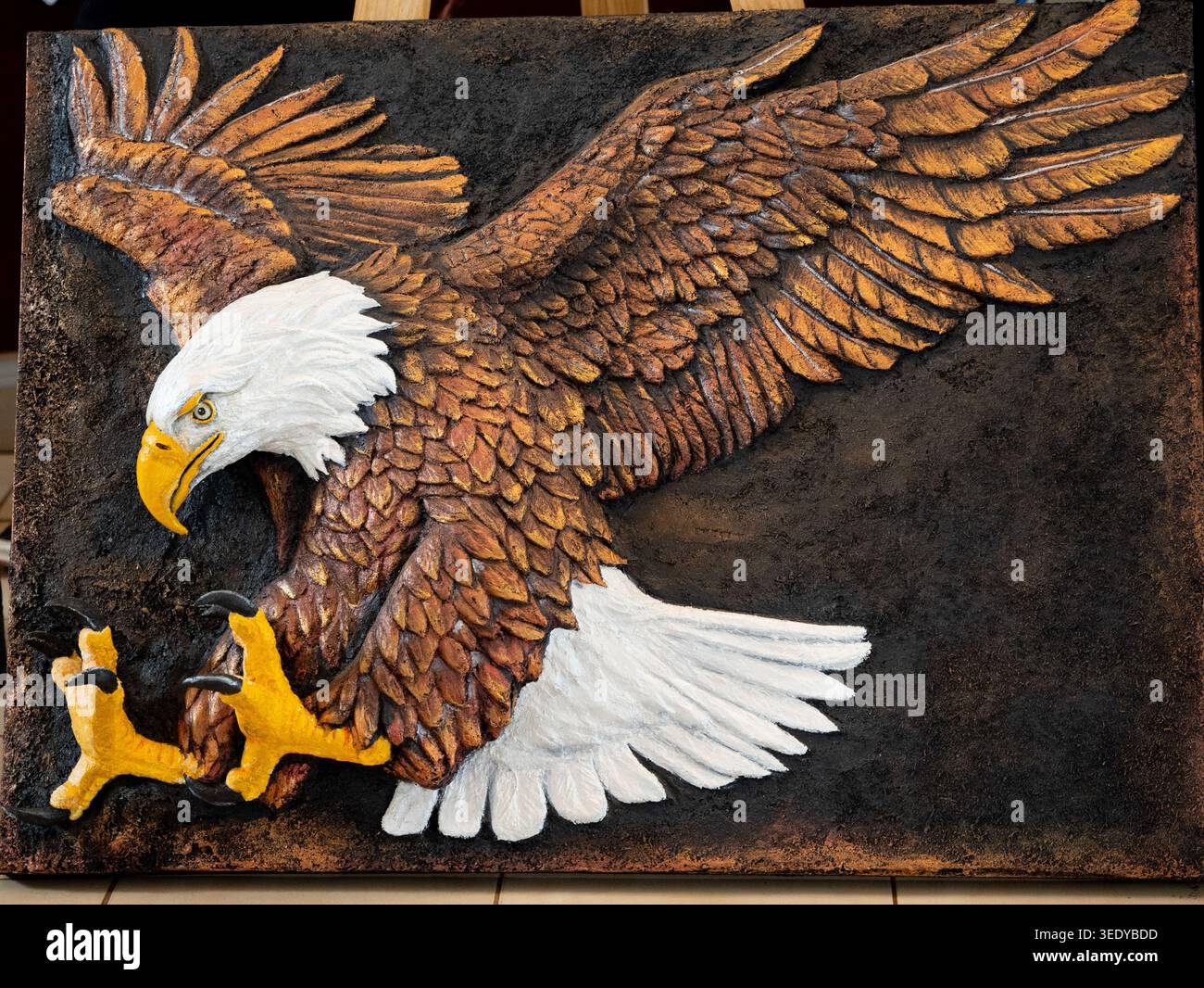 Ruanda, Kigali. Ein Kunstwerk zeigt einen mächtigen Weißkopfseeadler, der seine Flügel in der Mitte des Fluges ausbreitet, in einem reich strukturierten Reliefbild festgehalten. Stockfoto