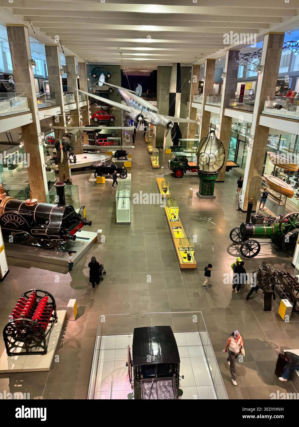 Historische Flugzeuge, Fahrzeuge und Industriemaschinen werden in der Ausstellungshalle des London Transport Museum ausgestellt, während Besucher den galler erkunden Stockfoto