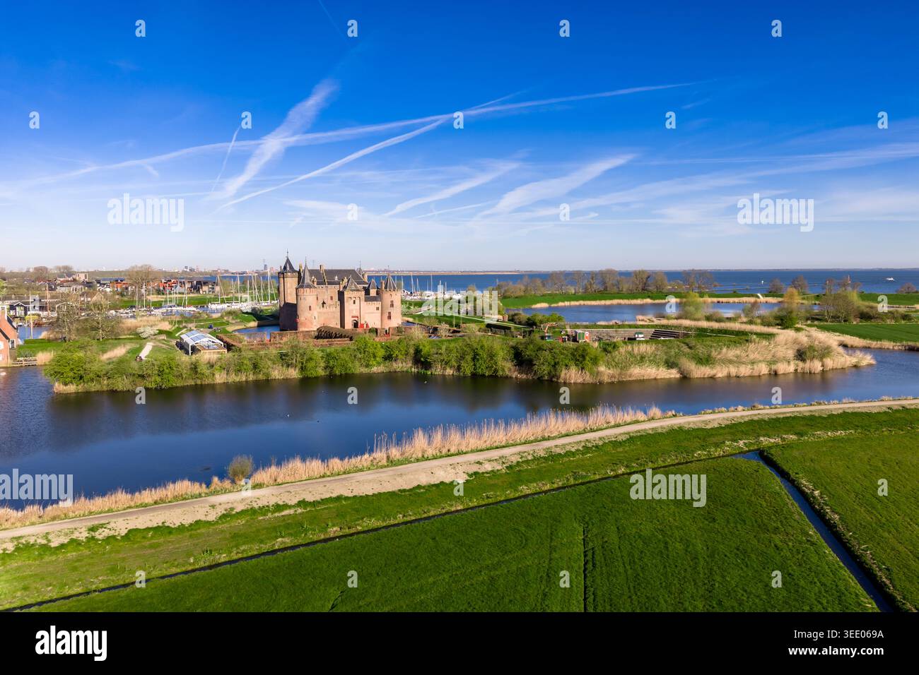 Die atemberaubende Landschaft der niederländischen Landschaft in der Nähe von Muiden, mit dem mittelalterlichen Muiderslot Castle, das über lebendige grüne Polderfelder sichtbar ist. Die Ve Stockfoto