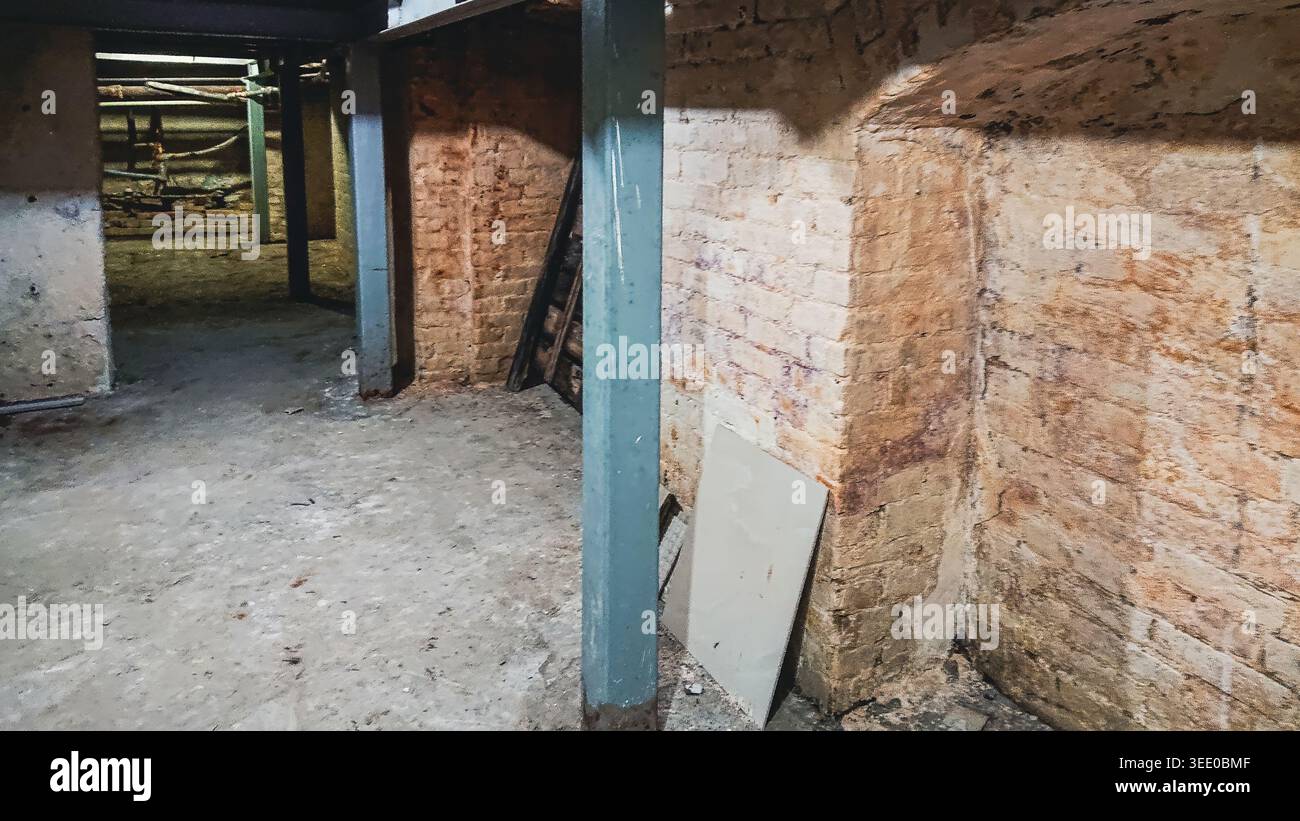 Nahaufnahme der baulichen Bewehrungsarbeiten im Keller eines alten Gebäudes mit Betonung von Ziegelwänden und Stützbalken Stockfoto
