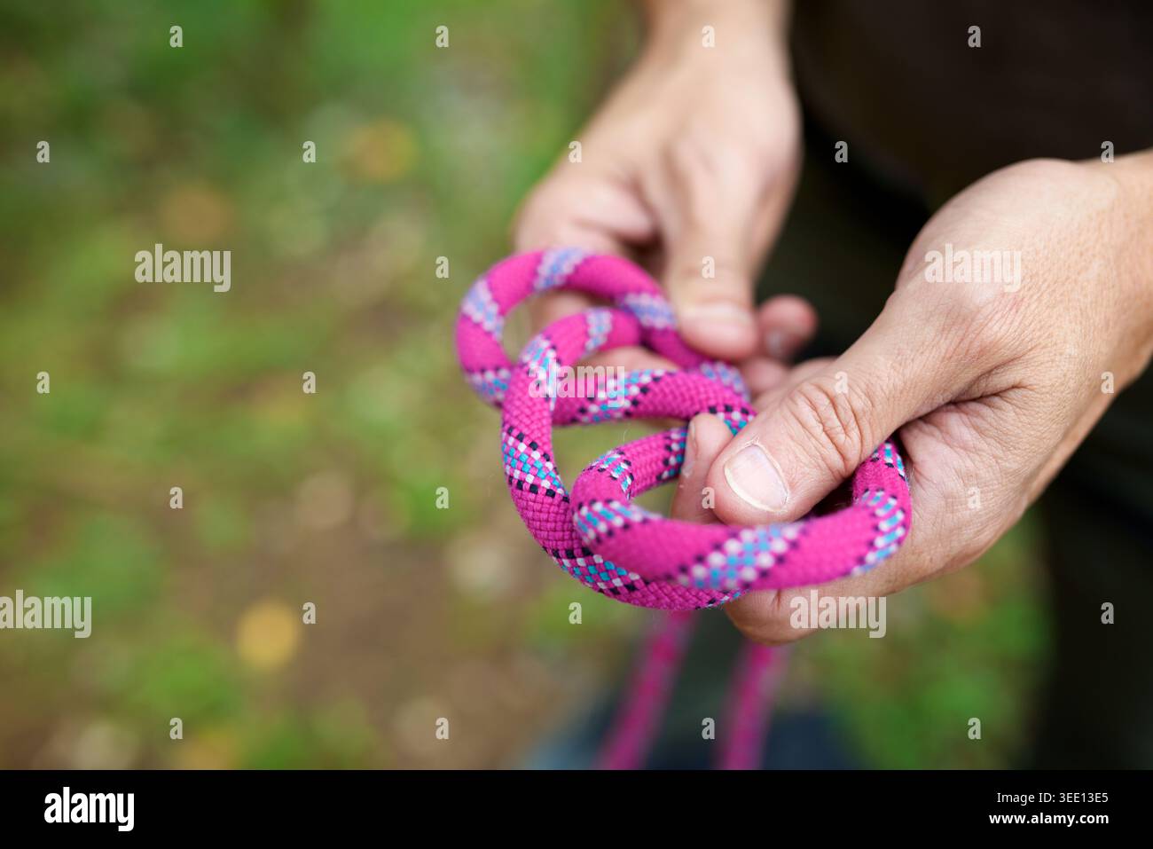 Nahaufnahme eines Kletterers, der das Kletterseil an seinem Klettergurt knüpft Stockfoto