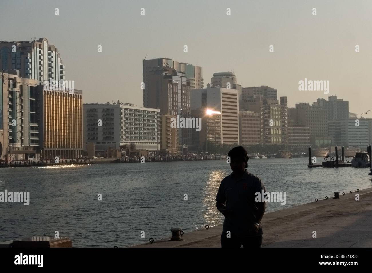 Silhouette eines Mannes am frühen Morgen, der entlang des Baches in Dubai, VAE, spaziert. Stockfoto