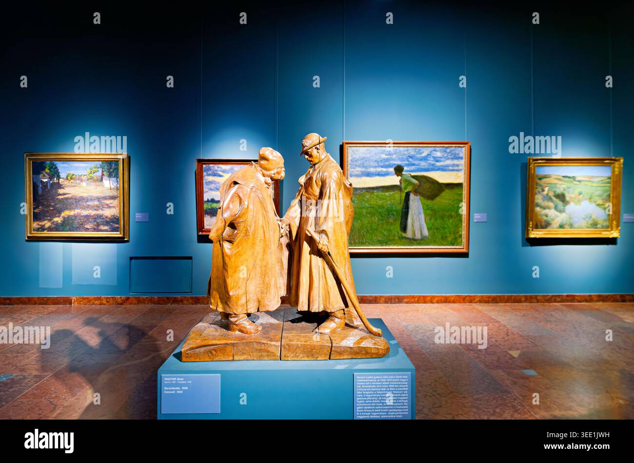 Besucher beobachten eine Holzskulptur zwischen Gemälden im BHM Castle Museum. Janos Pasztor. Abschied, 1906 Stockfoto