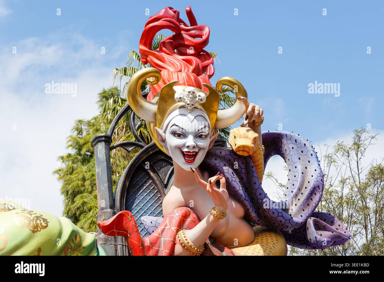 Farbenfrohe Las Fallas Festival Valencia Statue eines gehörnten Schurken mit roten Haaren, hellem Gesicht, Fledermausflügeln und einem gewundenen lila Schlangenschwanz gegen Blau Stockfoto