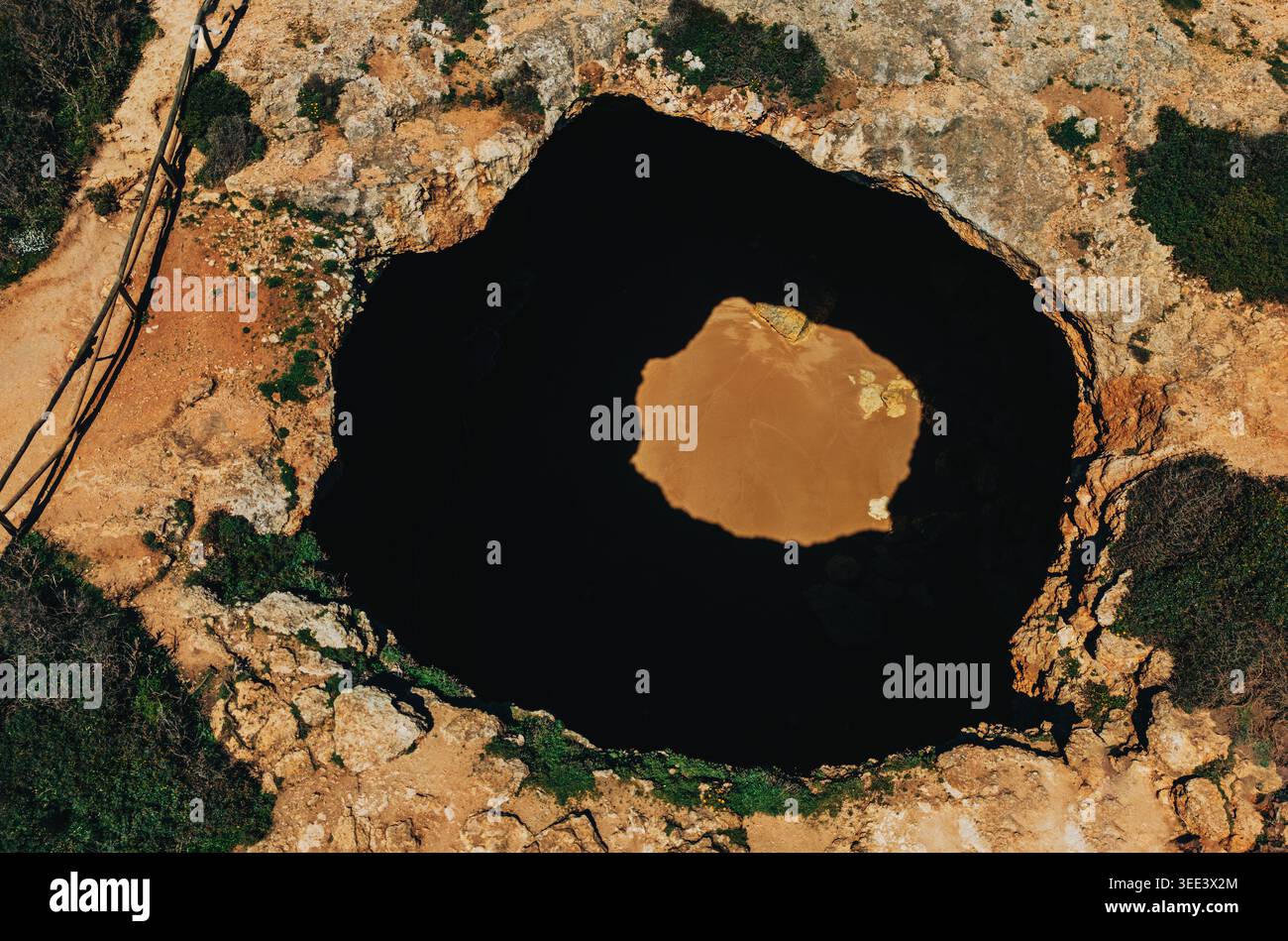 Blick aus der Vogelperspektive auf die massive Küstenhöhle mit verstecktem Sandstrand, umgeben von zerklüftetem felsigem Gelände und dramatischen Schatten. Portugal. Benagil Stockfoto